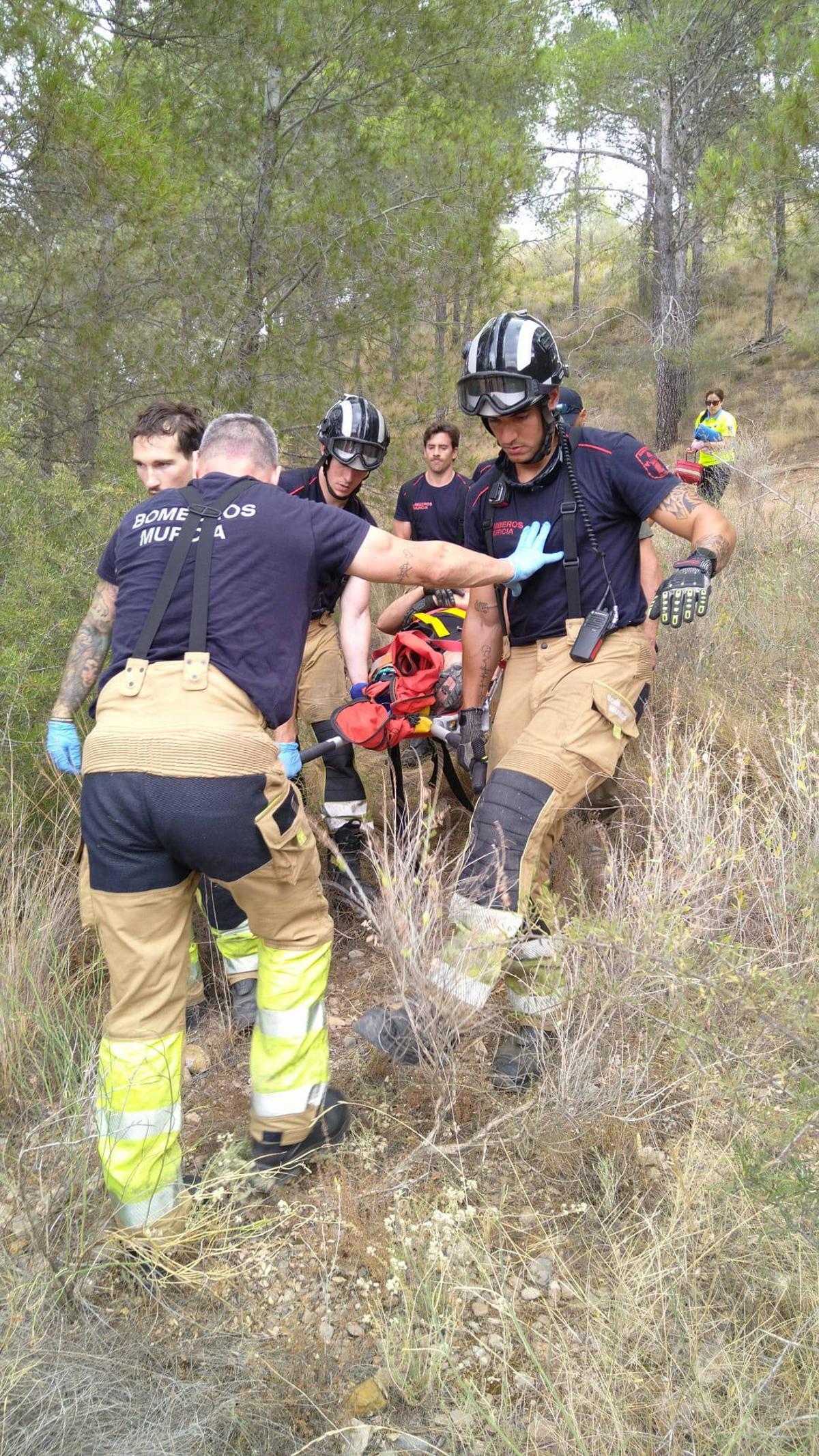 Los bomberos de Murcia bajan una cuesta con el ciclista herido en una camilla.
