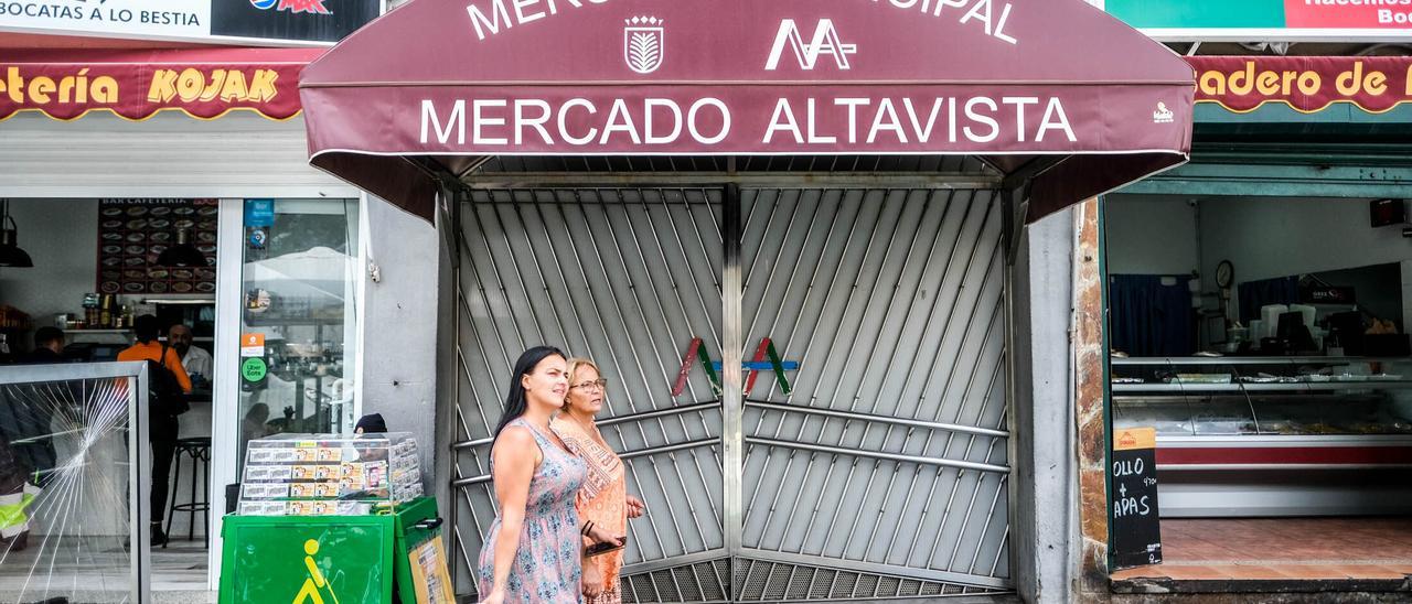 Dos mujeres pasan por la puerta cerrada del Mercado durante este martes.