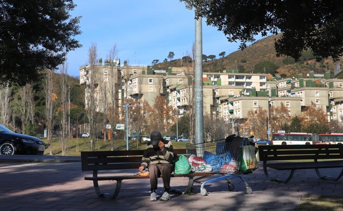 Una persona sin hogar, en un banco de la plaza Karl Marx, en Nou Barris.