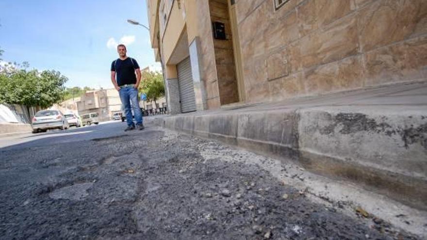 El concejal de IU muestra alguno de los socavones de la calzada.