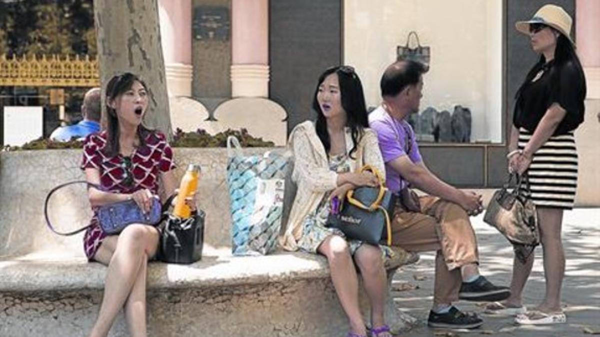 Unos turistas chinos descansan de sus compras en el paseo de Gràcia.