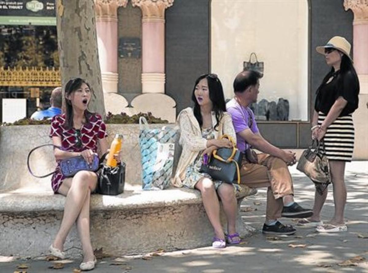 Uns turistes xinesos descansen de les compres al passeig de Gràcia, ahir.