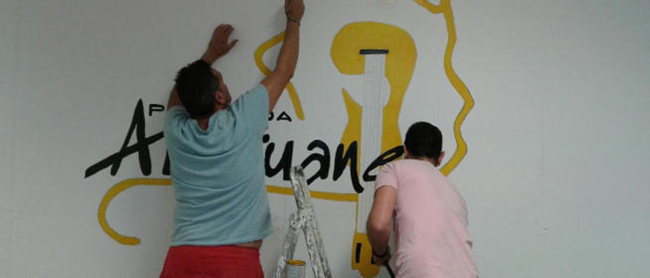 Dos integrantes del grupo pintan su logo en la pared del nuevo local.