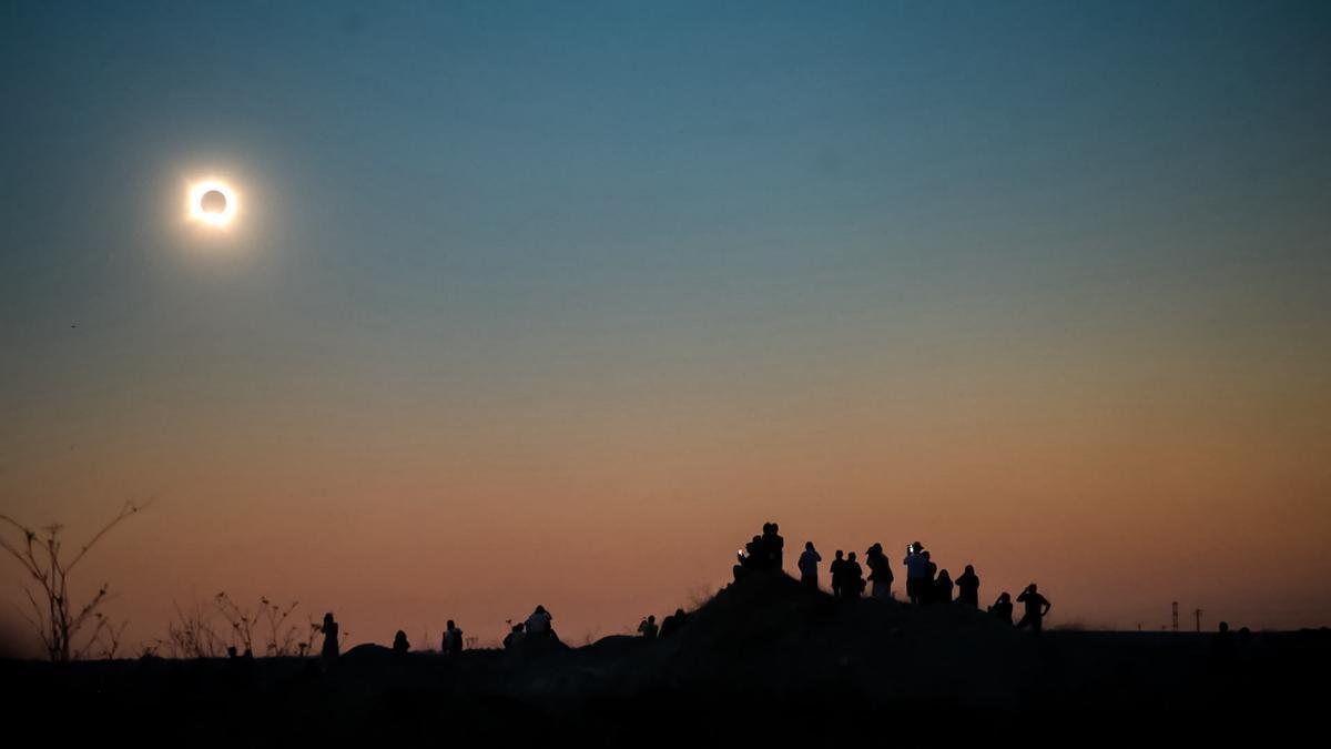 La gente fotografía en el polígono de La Hiniesta el eclipse solar instantes antes de que sea total.