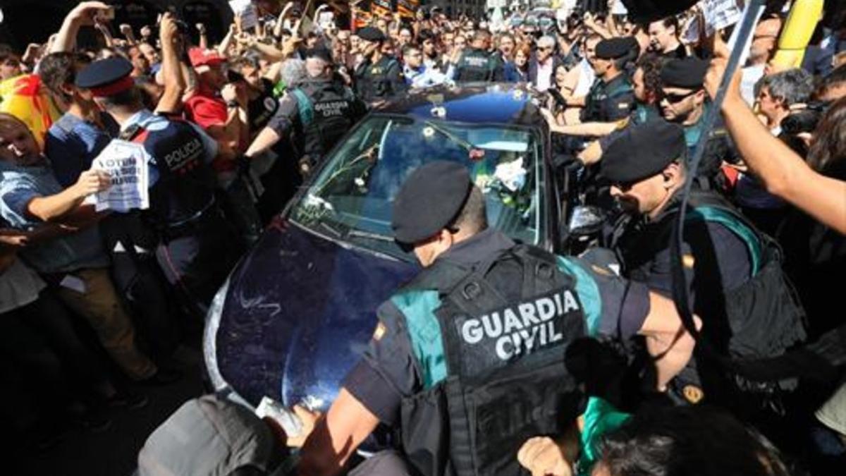 Mossos ayudan a guardias civiles a salir de una concentración de protesta ante la Conselleria d'Afers Exteriors.