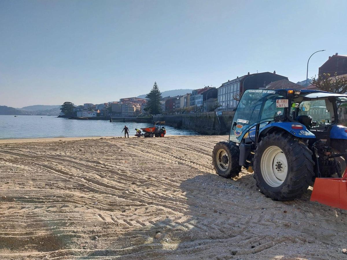 La brigada municipal trabajando esta semana en la limpieza de una de las playas del centro de Bueu.