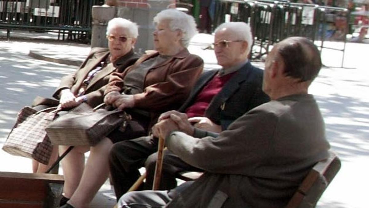 Gente mayor sentada en unos bancos en L'Hospitalet de Llobregat.