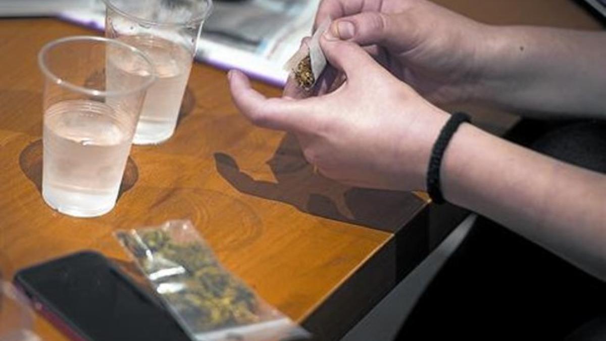 Un socio de un club prepara un porro de marihuana.