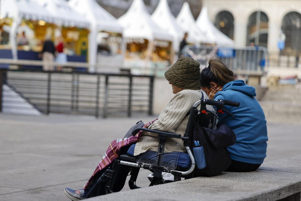 Una cuidadora permanece sentada con la mujer mayor a la que asiste. EFE/Mariscal