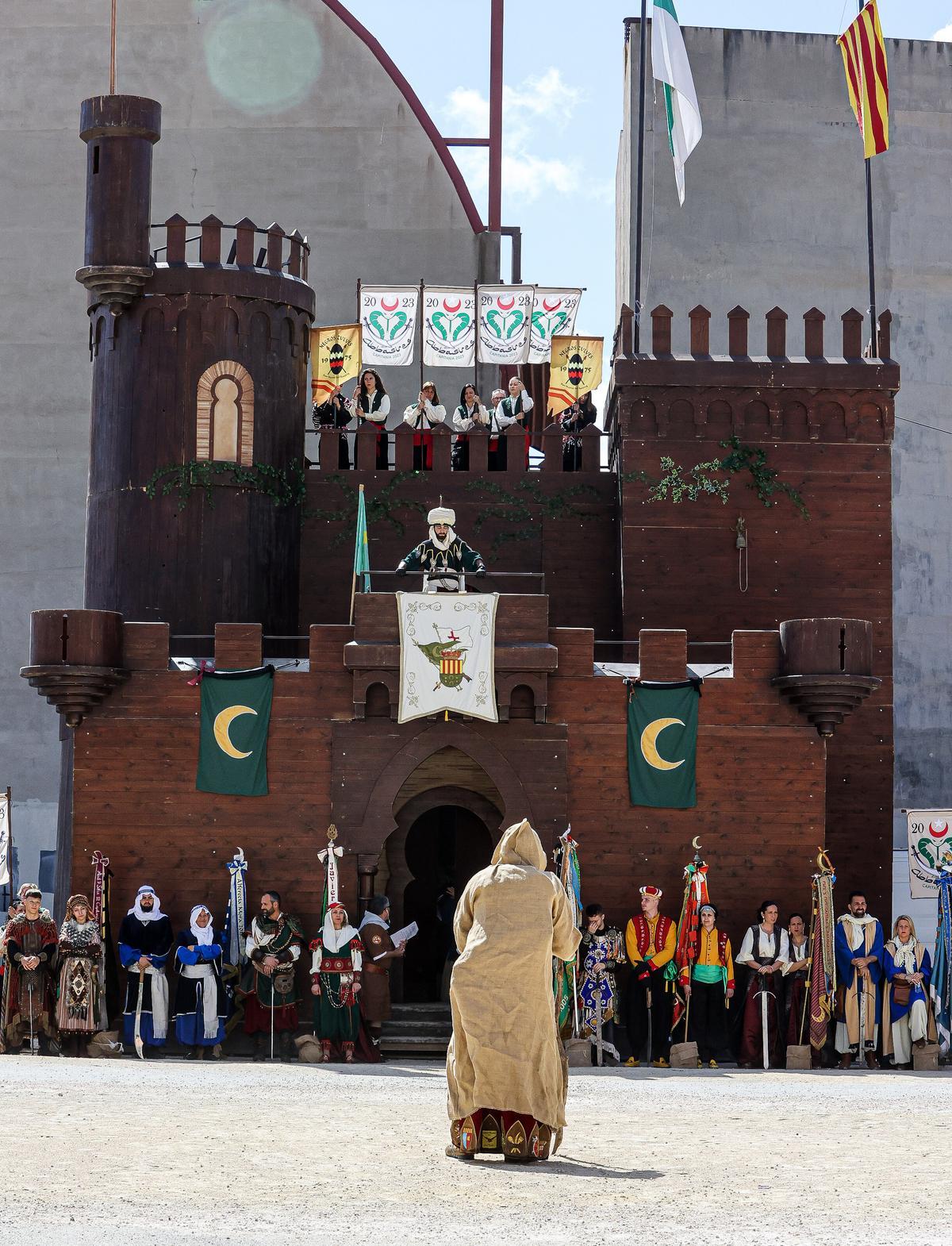El embajador cristiano vestido de mendigo ante el castillo, que guardan los estandartes de las comparsas moras.