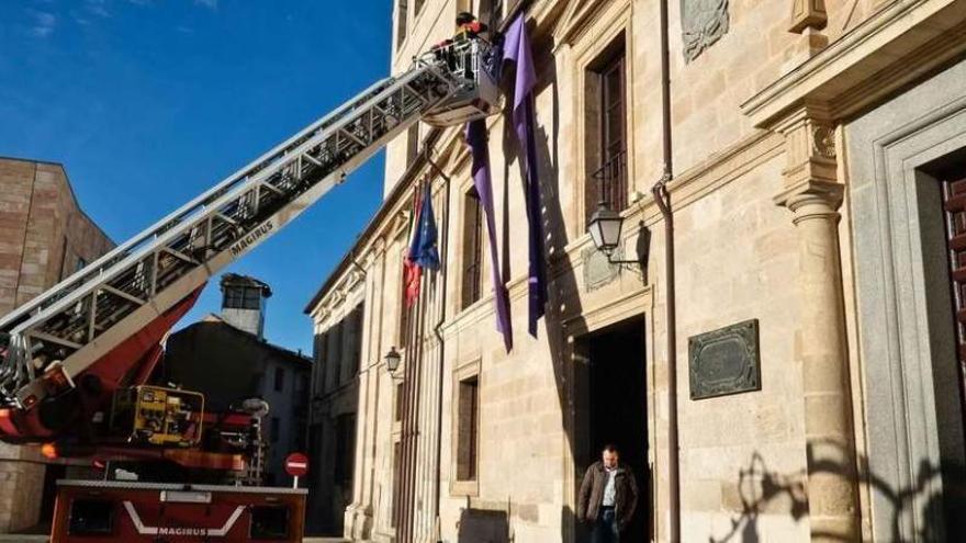 Los bomberos colocan el lazo violeta en la fachada de la Diputación Provincial.