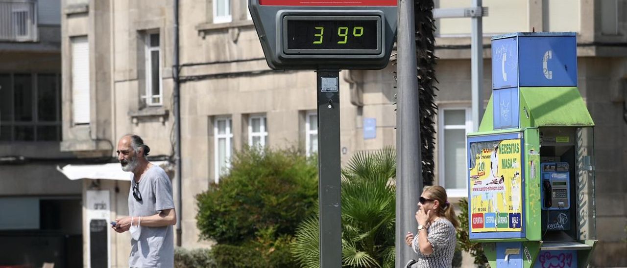 Varias personas transitan ante un termómetro al sol que ayer marcaba 39 grados en Pontevedra, aunque realmente se llegó hasta los 35,5 grados.