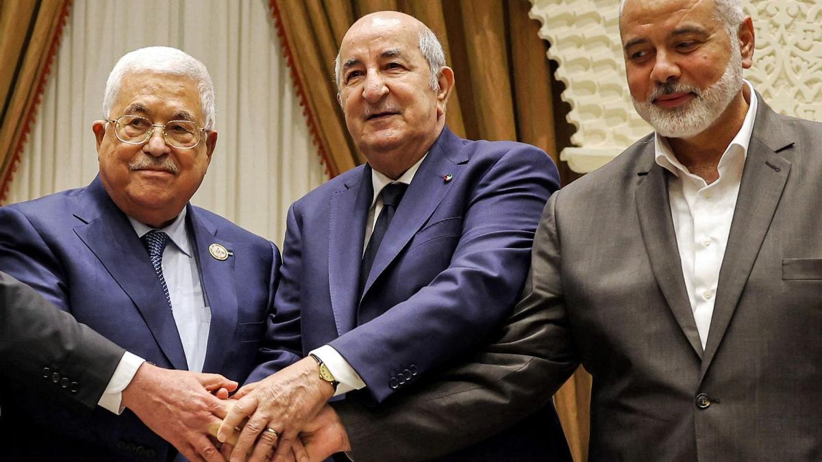 De izquierda a derecha, el presidente de la Autoridad Palestina Mahmud Abbás junta sus manos con las del presidente de Argelia, Abdelmajid Tebboune, y las del líder de Hamás, Ismail Haniyed.