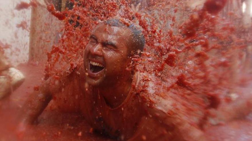 Un joven se lanza sobre el suelo cubierto de tomate, hoy, en la Tomatina.