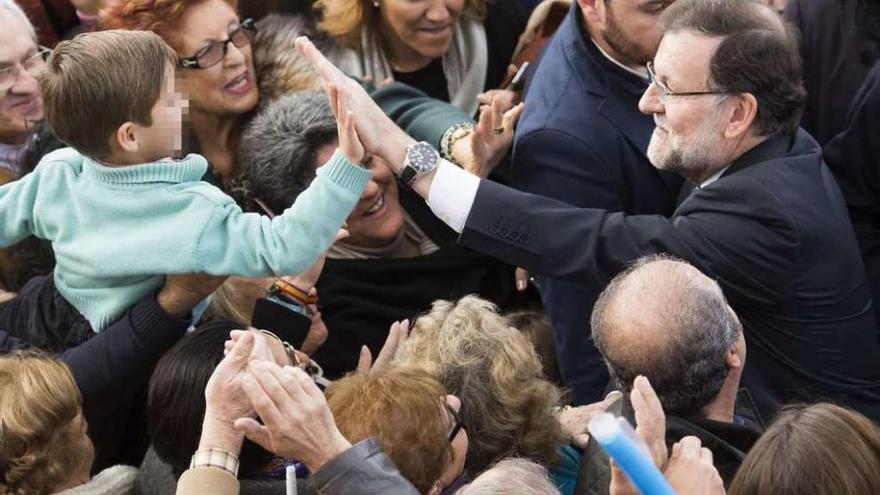 El presidente del Gobierno, Mariano Rajoy, saluda a un niño a su llegada al mitin de Sevilla.