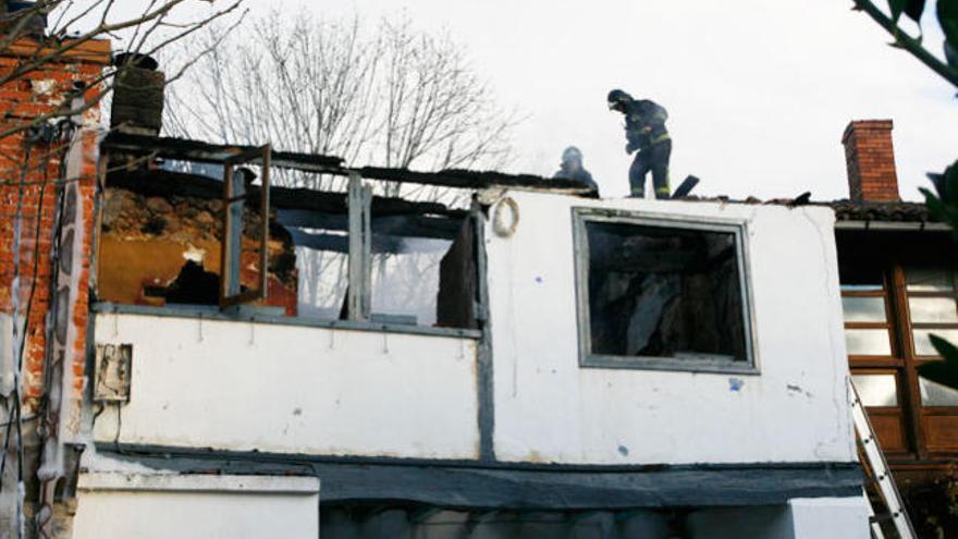 Dos bomberos trabajan en una de las viviendas calcinadas. /