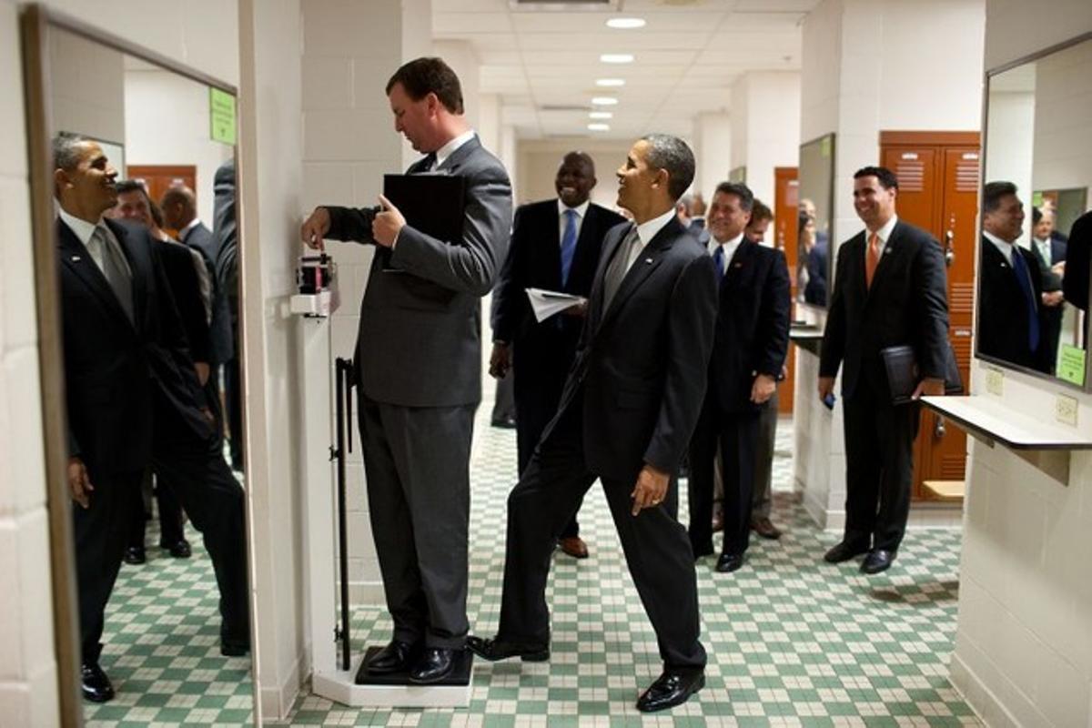 Marvin Nicholson, director de viajes del presidente, se pesa en una báscula mientras Obama bromea con él, en agosto del 2010.