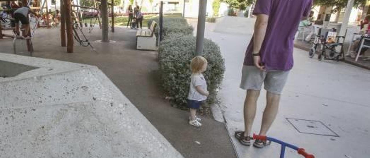 Un pequeño junto a su padre en el parque infantil de la plaza de Séneca.