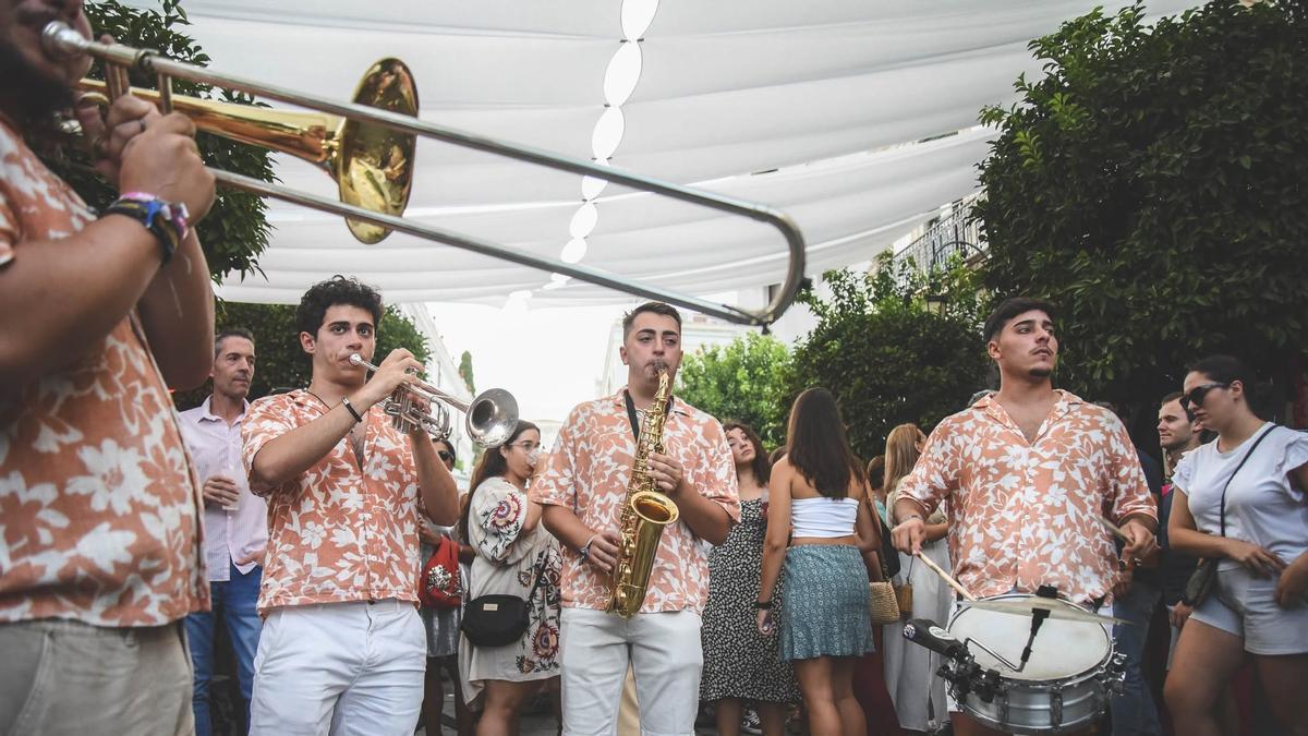 Los músicos de una charanga actúan entre los asistentes en pleno centro de Mérida.