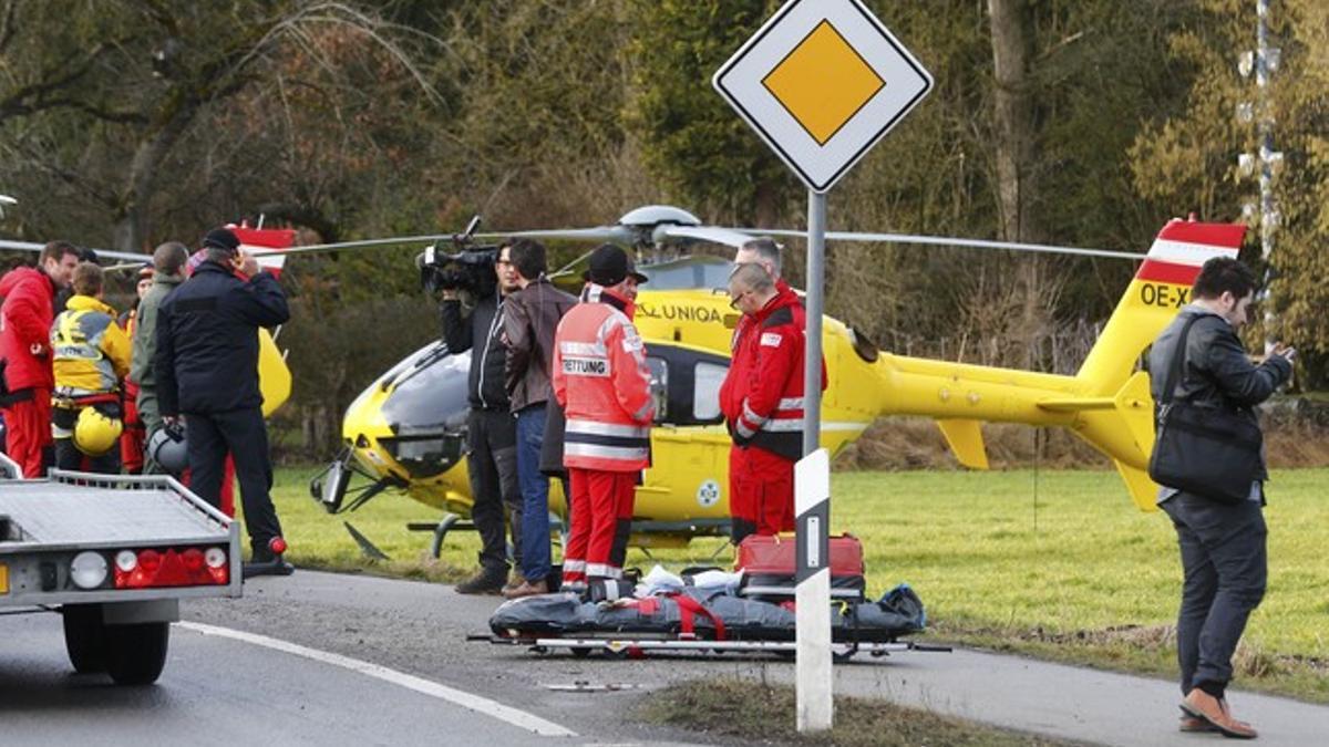 Rescuers and journalists stand in front of a rescue helicopter near Bad Aibling