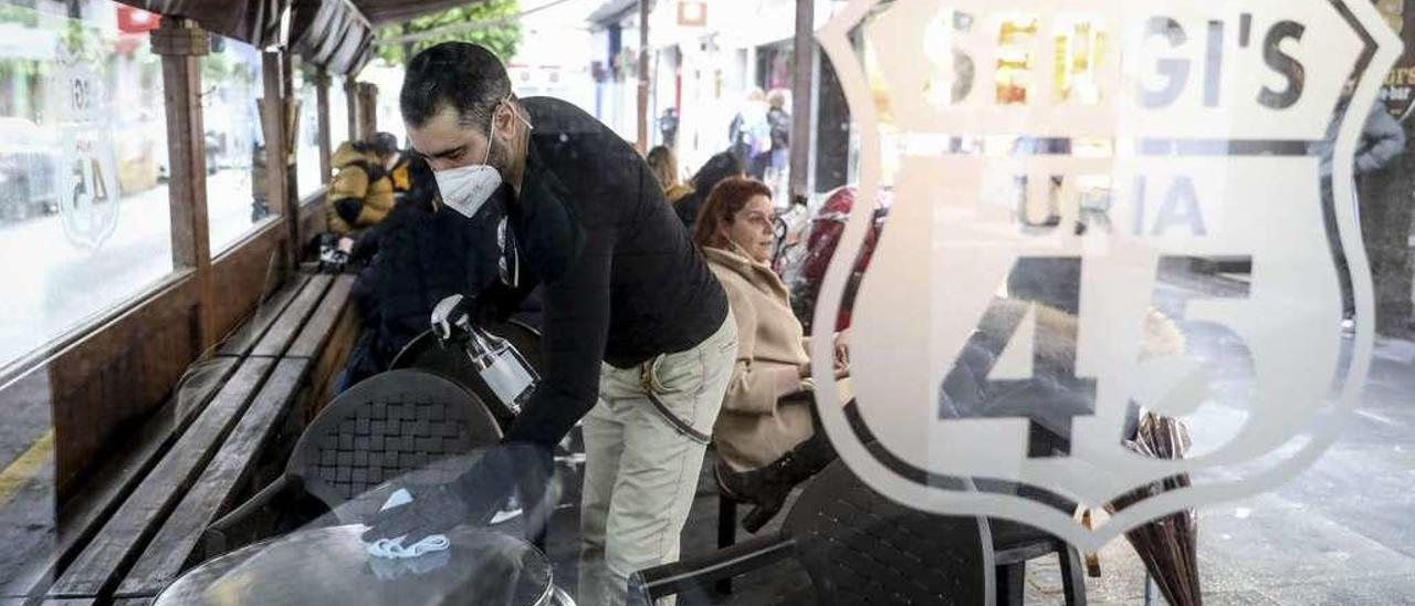 Sergio Cosío, en su terraza de Uría. A la izquierda, Ana María Cascais sirve un café en la calle Concepción Arenal.