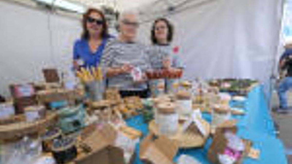 Madre, abuela e hija en un puesto de artesanía de velas.