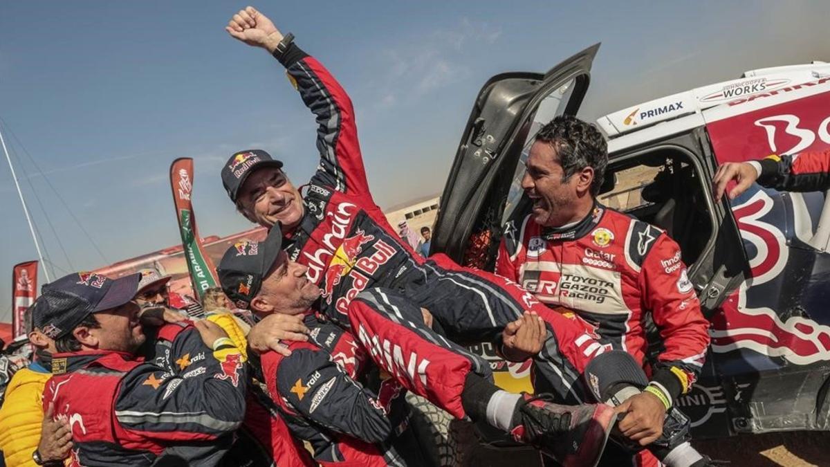 Sus amigos Stephane Peterhansel y Nasser Al-Attiyah levantan a Carlos Sainz, como ganador del Dakar-2020.