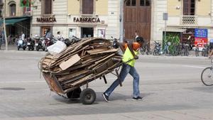 Un nmigrante africano lleva un carrito lleno de cartones.