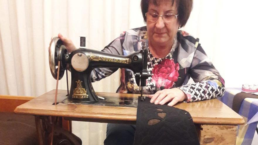 María Pérez Blanco, artesana de Bercianos, sentada a la máquina de coser con una capa. | Ch. S.