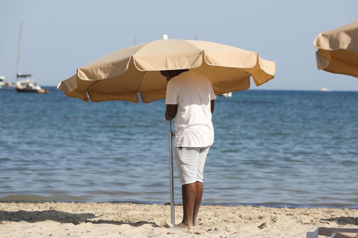 Un hombre instala una sombrilla en una playa en una imagen de archivo