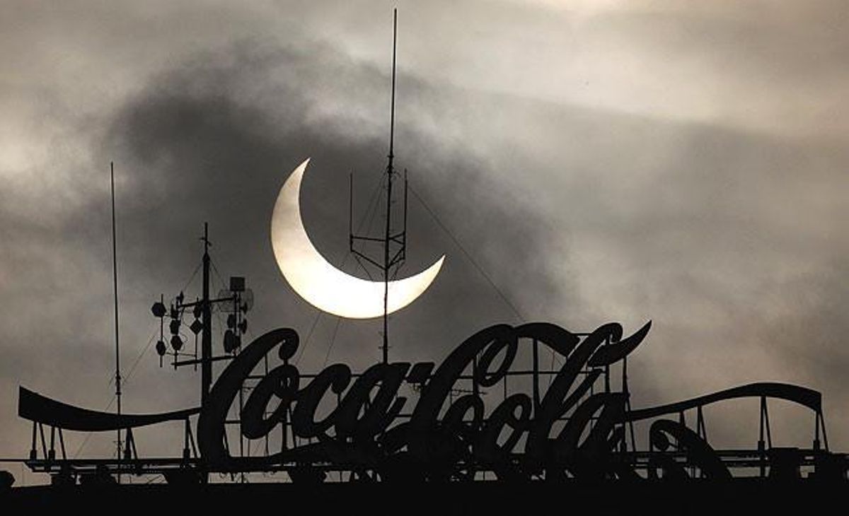 L’eclipsi és visible darrere d’un cartell de la Coca-Cola, sobre la ciutat de Varsòvia (Polònia).