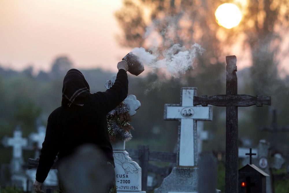 A woman burns incense near the grave of departed ...