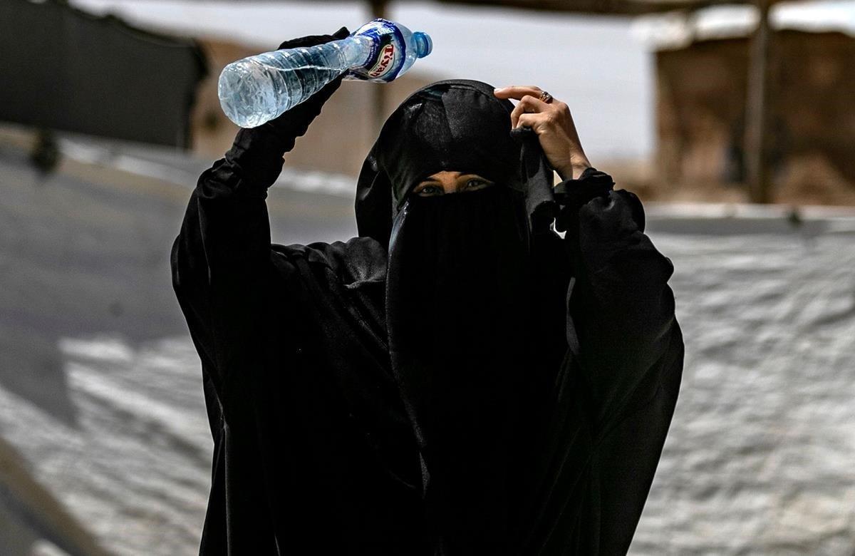 Una mujer se refresca en del campamento de al-Hol. Alrededor de 800 mujeres salieron hoy del campamento de desplazados de Al Hol, en la provincia siria de Al Hasaka (noreste), entre ellas familiares de miembros del grupo terrorista Estado Islámico (EI).