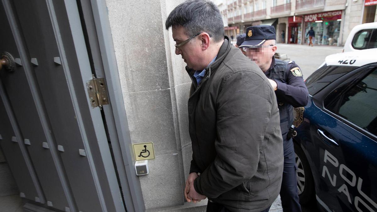 Un agente de Policía Nacional lleva al acusado del triple crimen, José Luis Abet, a la Audiencia Provincial de Pontevedra esta mañana
