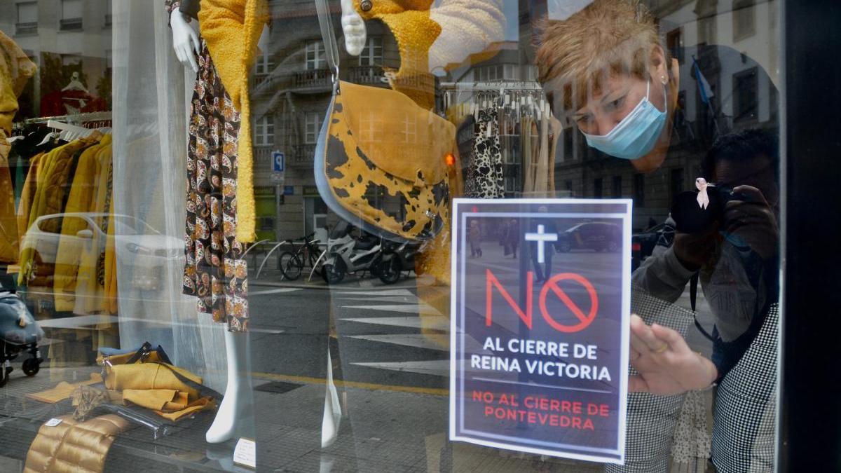 Una de las comerciantes de Reina Victoria cuelga el cartel contra el cierre de la calle. // R. Vázquez