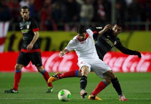 Sevilla's Jorge Coke and Atletico Madrid's Arda Turan fight for the ball during their Spanish King's Cup semifinal second leg soccer match at Ramon Sanchez Pizjuan stadium in Seville