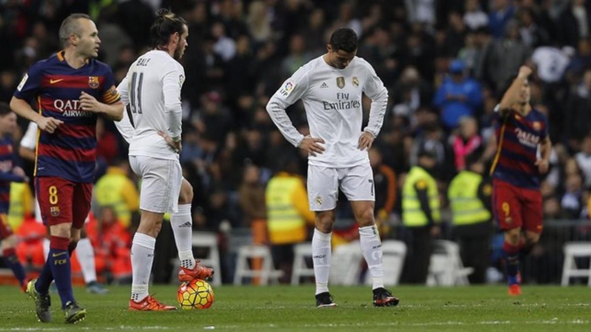 Bale y Cristiano esperan a poder hacer el saque de centro a que Iniesta (izquierda9 y Suárez (derecha) regresen a su parcela tras un gol del Barça.