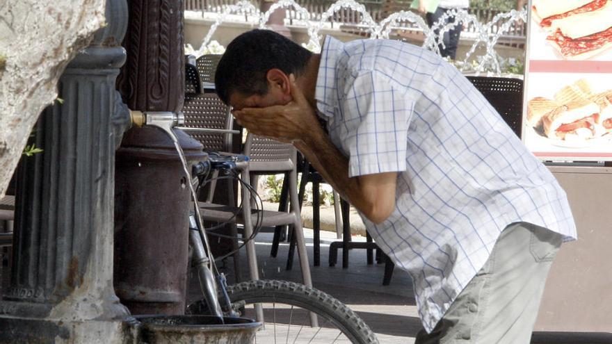 Un hombre se refresca con agua de una fuente debido al calor