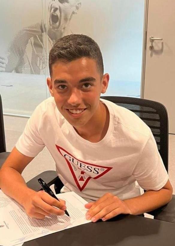 El alumno del Sagrada Familia de Elda firmando el contrato tras ser fichado por el club colchonero.