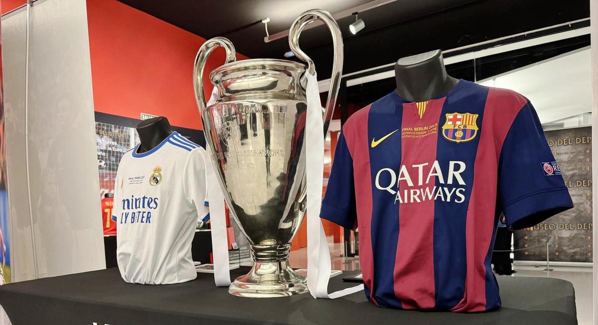 El trofeo de la Liga de Campeones de fútbol, junto a las camisetas del Real Madrid y el FC Barcelona.
