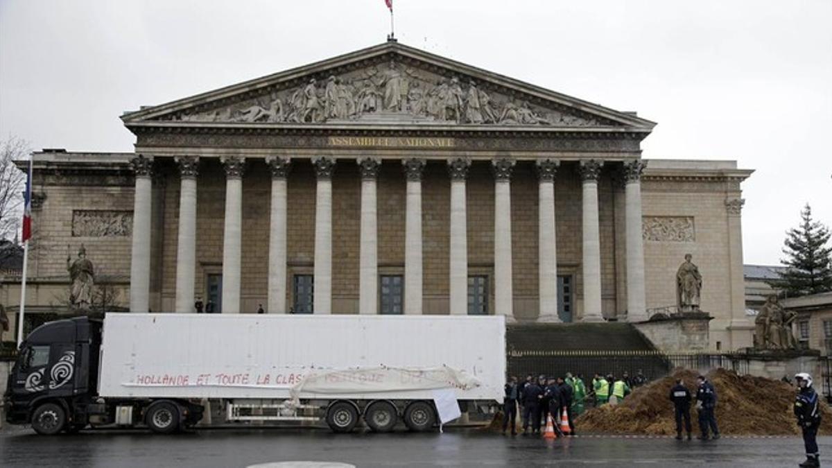 Agentes franceses permanecen junto al camión que ha vertido su carga de estiércol, esta mañana en París.