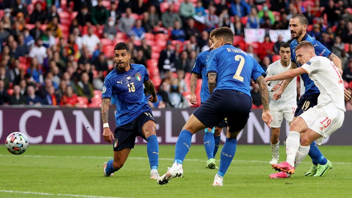 Dani Olmo dispara rodeado de cuatro defensas italianos.