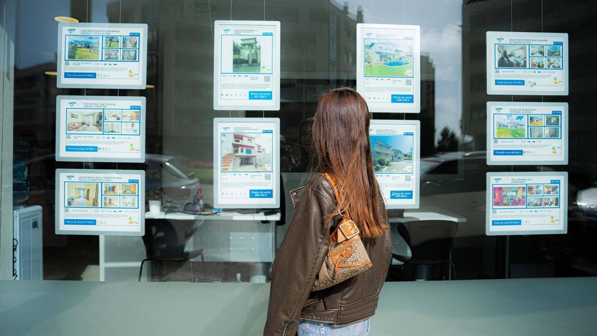 Una joven observa el escaparate de una inmobiliaria.