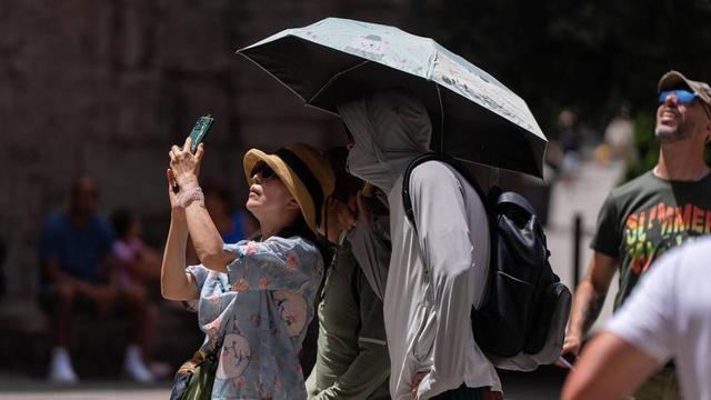 Turistes es refugien del sol durant una jornada de calor extrema a Barcelona.