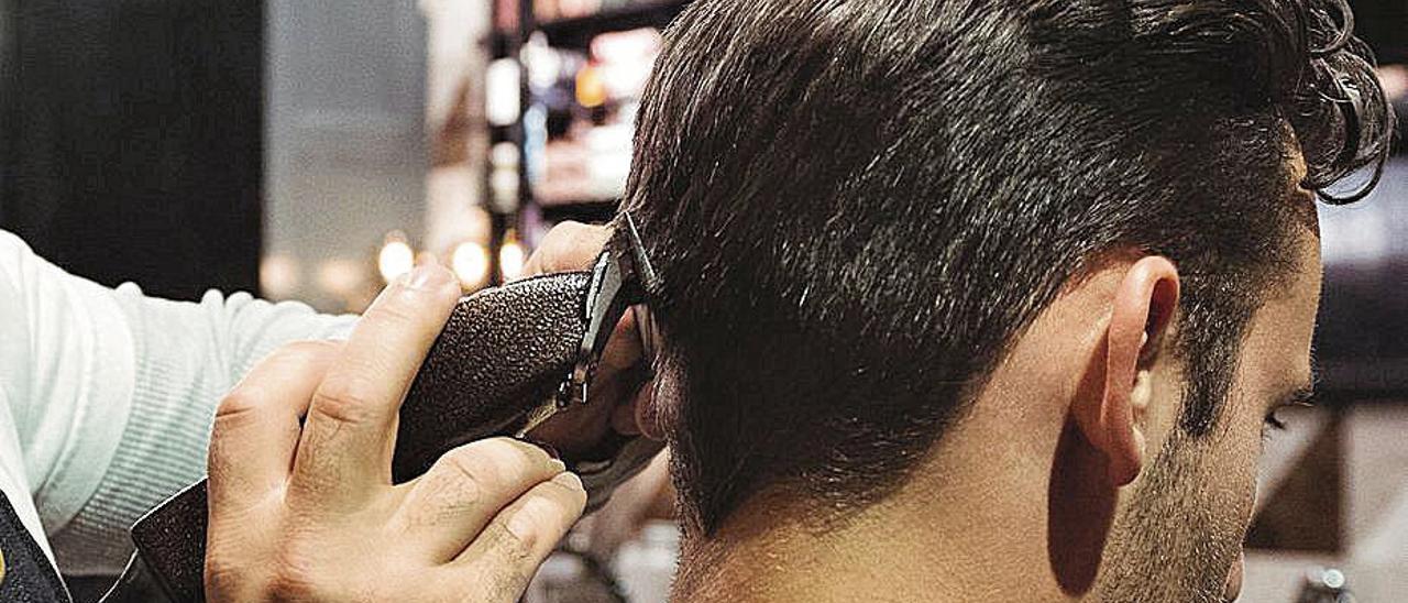 Un joven, mientras le rasuran el pelo en una peluquería.