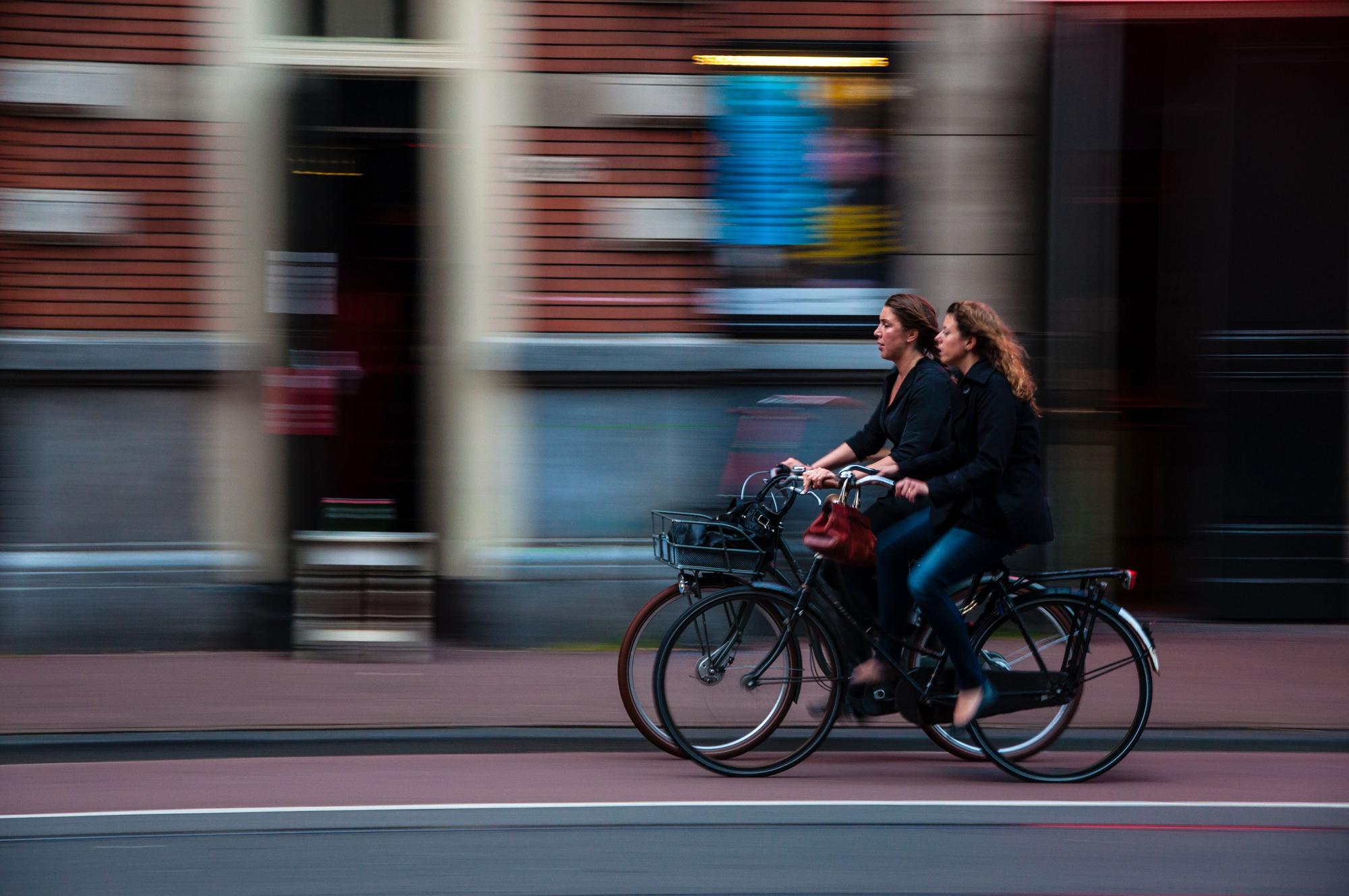 Dos mujeres circulan en bicicleta por una ciudad.