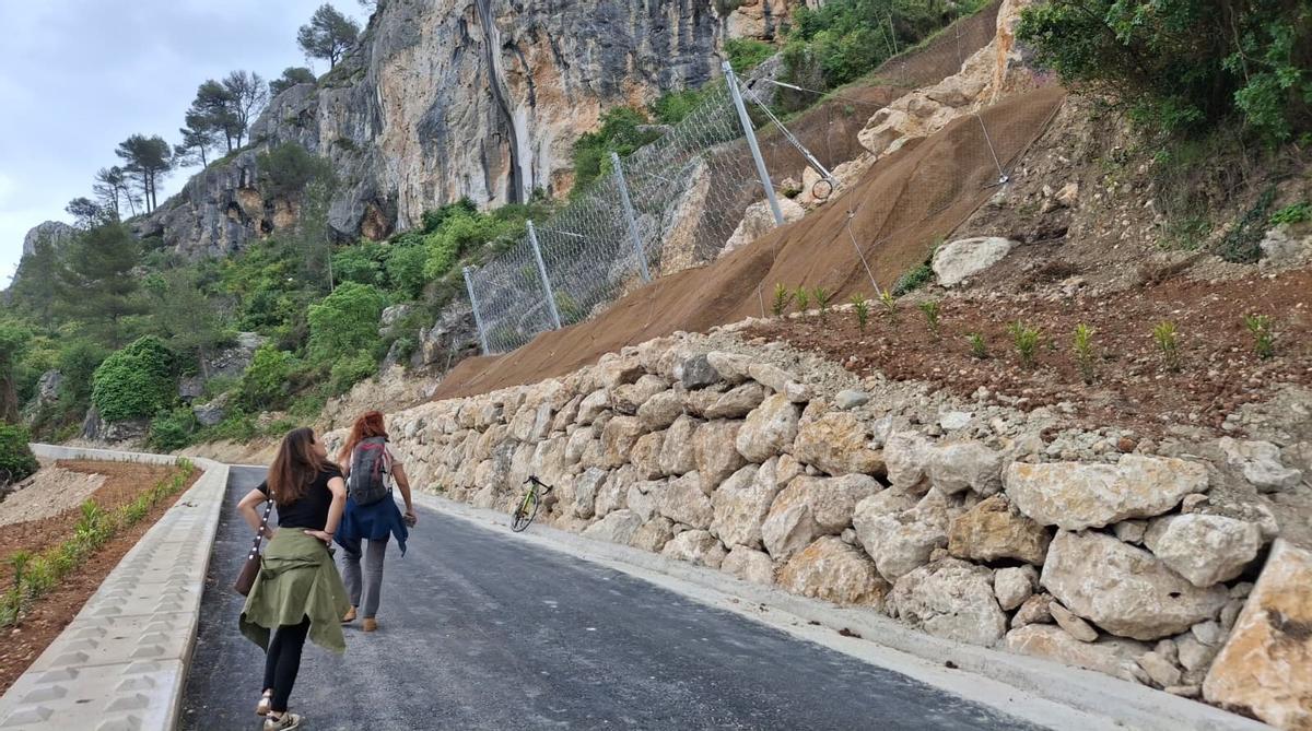 Dos senderistas observan el muro de piedras de escollera y la barrera dinámica