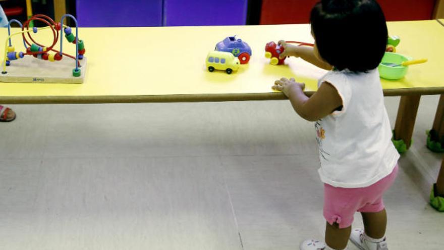 Una niña se distrae jugando con unos coches de juguete en su centro infantil.