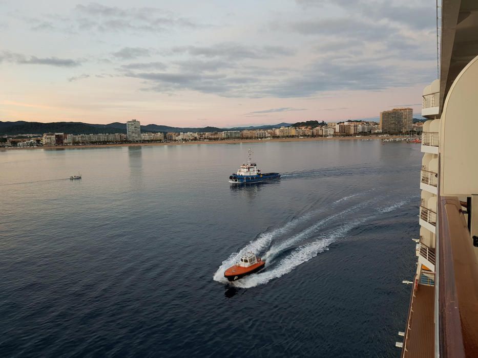 La llanxa del pràctic i el remolcador París escorten el Seven Seas Explorer mentre surt de la zona portuària de Palamós.