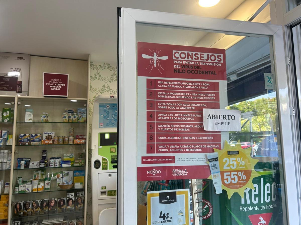 Un cartel preventivo de Consejos contra la transmisión del Virus del Nilo en la puerta de una farmacia de Sevilla.